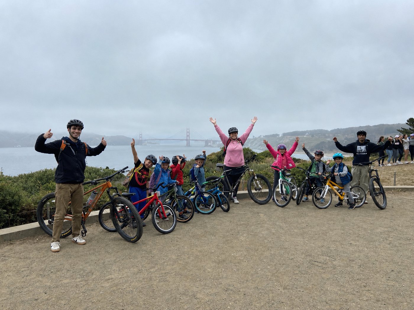 Children and bike coaches celebrating during a group bicycle lesson near the Golden Gate Bridge in San Francisco