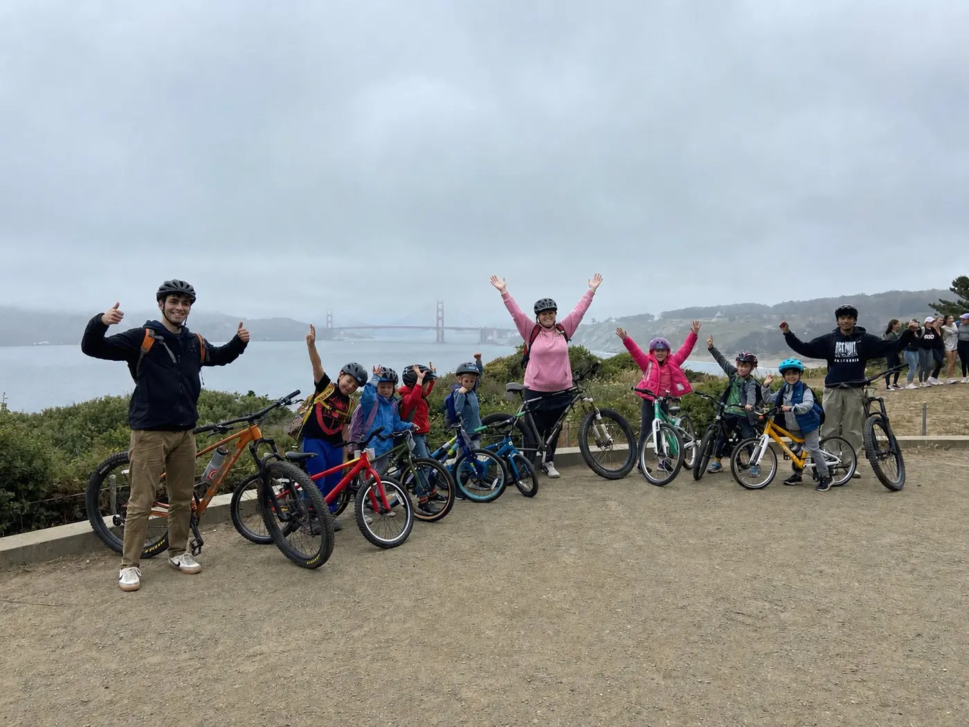 Young riders and bike coaches celebrating after a confidence-building lesson near the Golden Gate Bridge